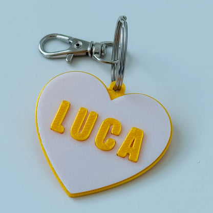 Heart-shaped Dog name tag with 'LUCA' on a white background