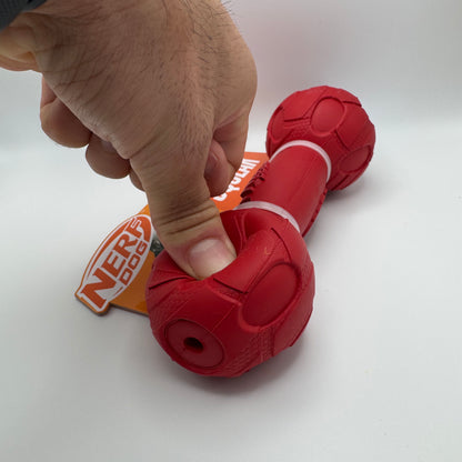 Red Nerf dog toy with a hand holding it on a white background