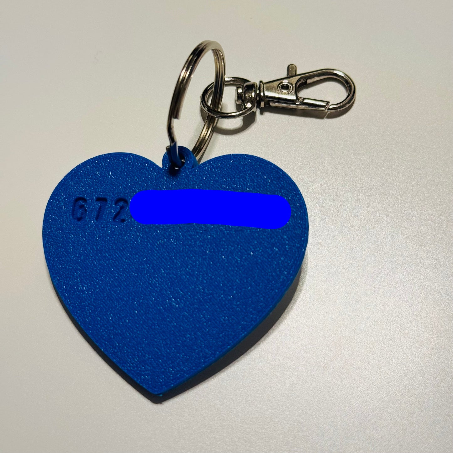 Blue heart-shaped keychain dog name tag with text on a white background