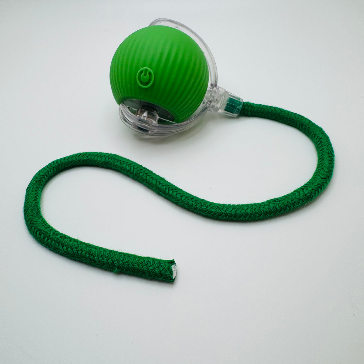 Green Vibrating Bouncing Ball Toy with a dark green rope tail, angled view