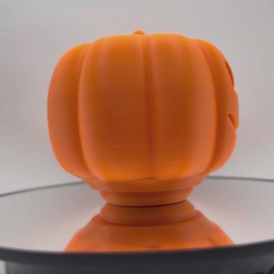 Orange pumpkin treat dispenser turning 360 degrees to show the carved face from every side