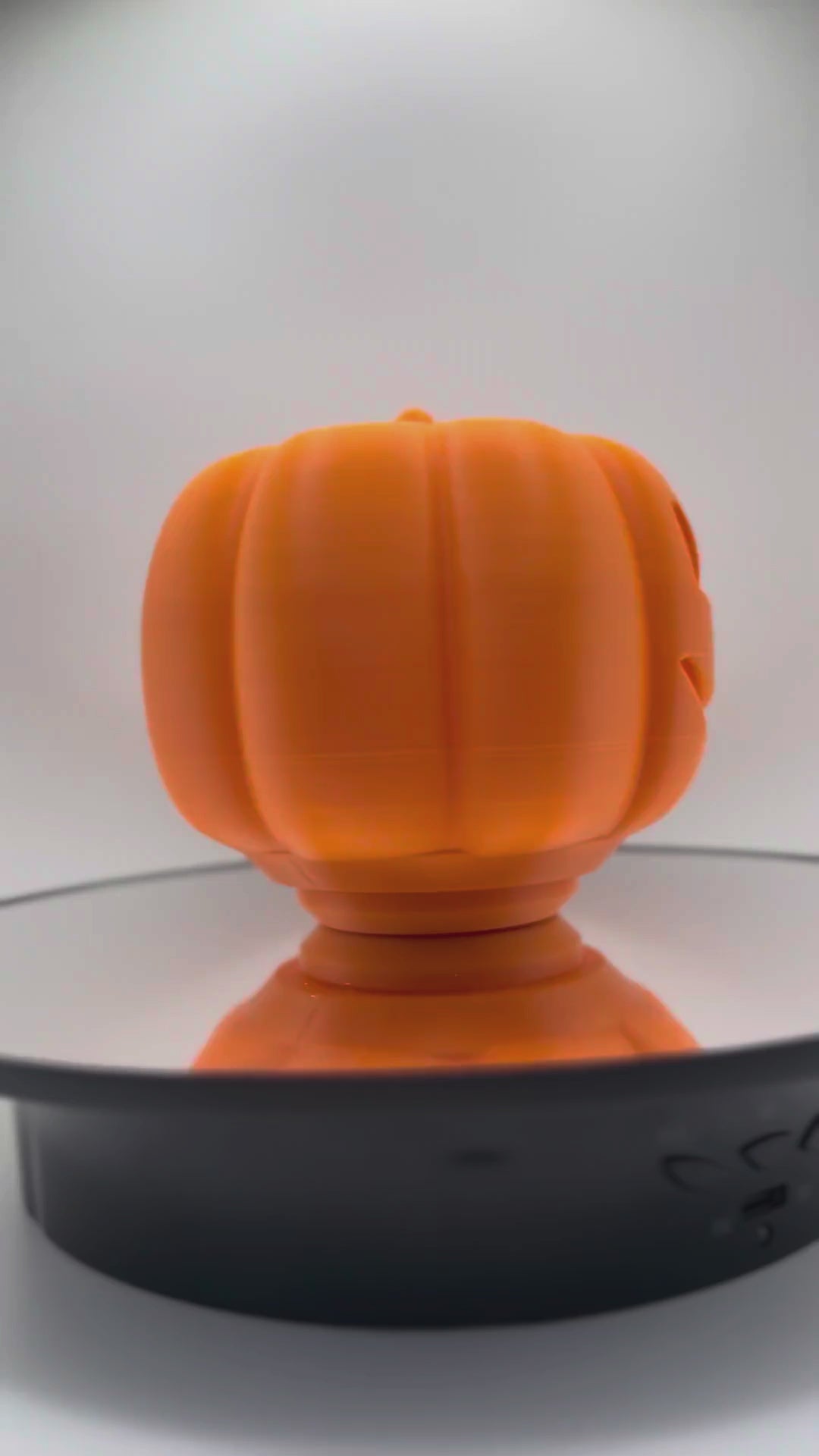 Orange pumpkin treat dispenser turning 360 degrees to show the carved face from every side