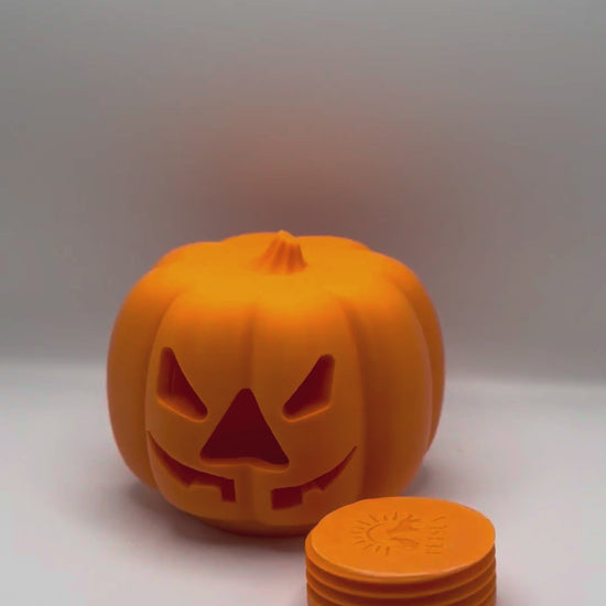 Hands unscrewing the threaded bottom plug of the pumpkin treat dispenser to fill it