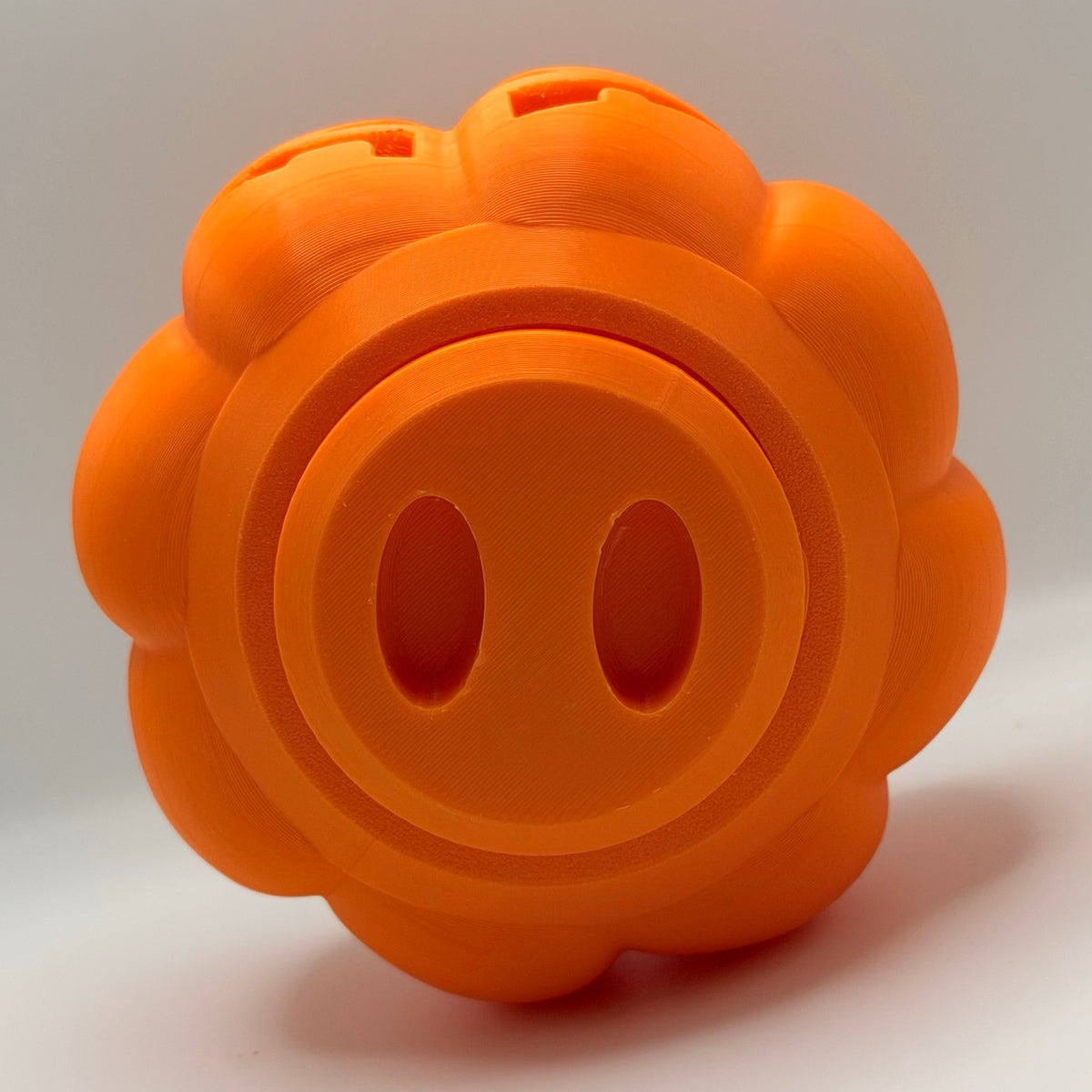 Orange pumpkin treat dispenser for dogs and cats, bottom view showing the fill plug