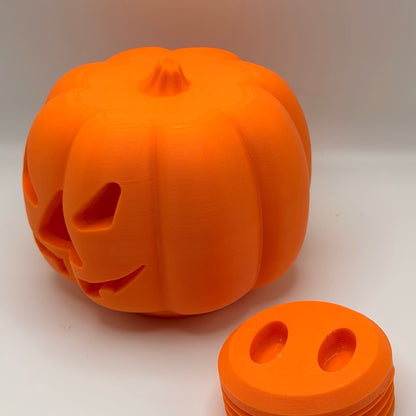 Orange pumpkin treat dispenser for dogs and cats, with its threaded bottom plug