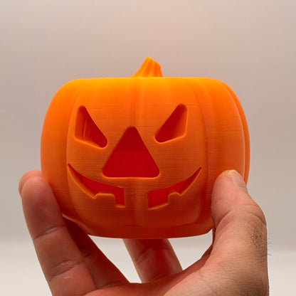 Orange pumpkin treat dispenser for dogs and cats, held in a hand to show size