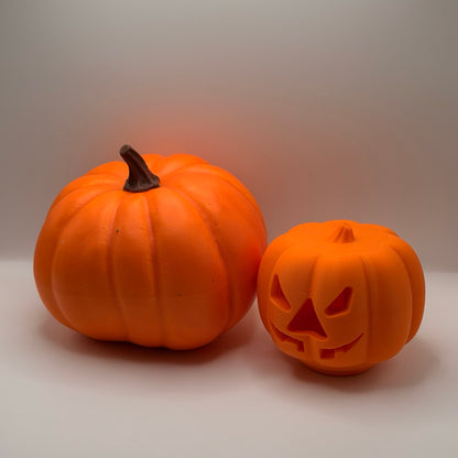 Orange pumpkin treat dispenser for dogs and cats, next to a real pumpkin